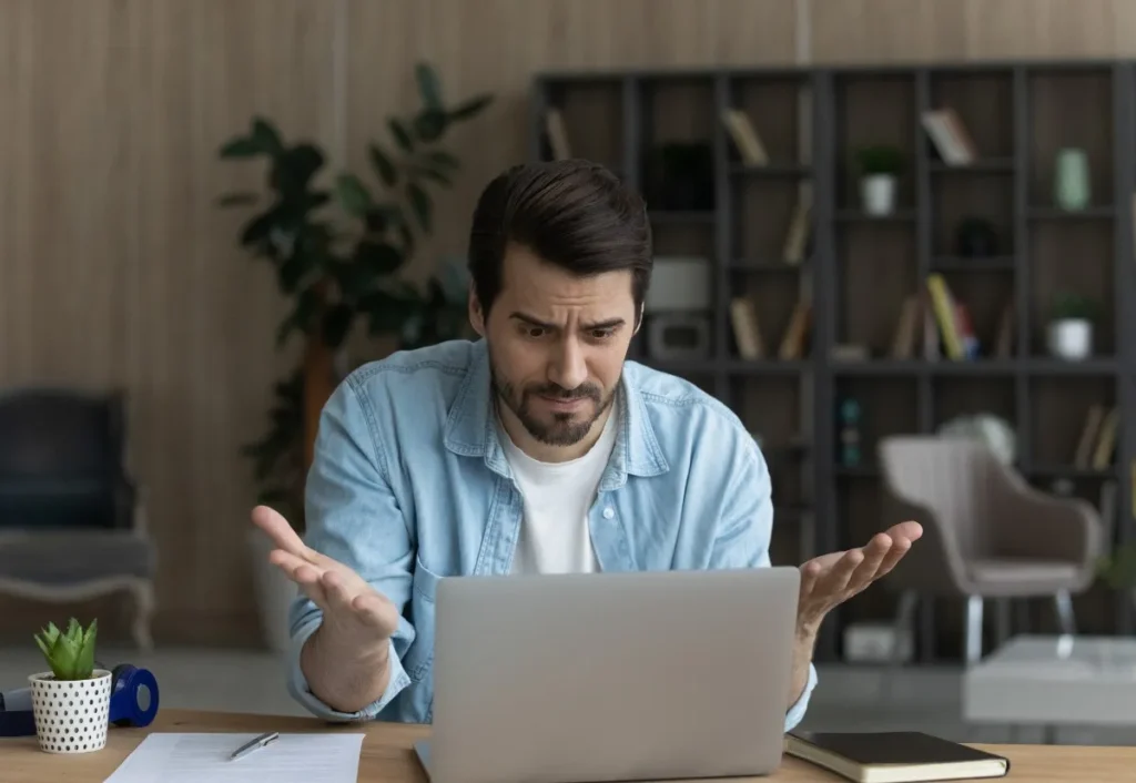 homem frustrado com algo em seu notebook