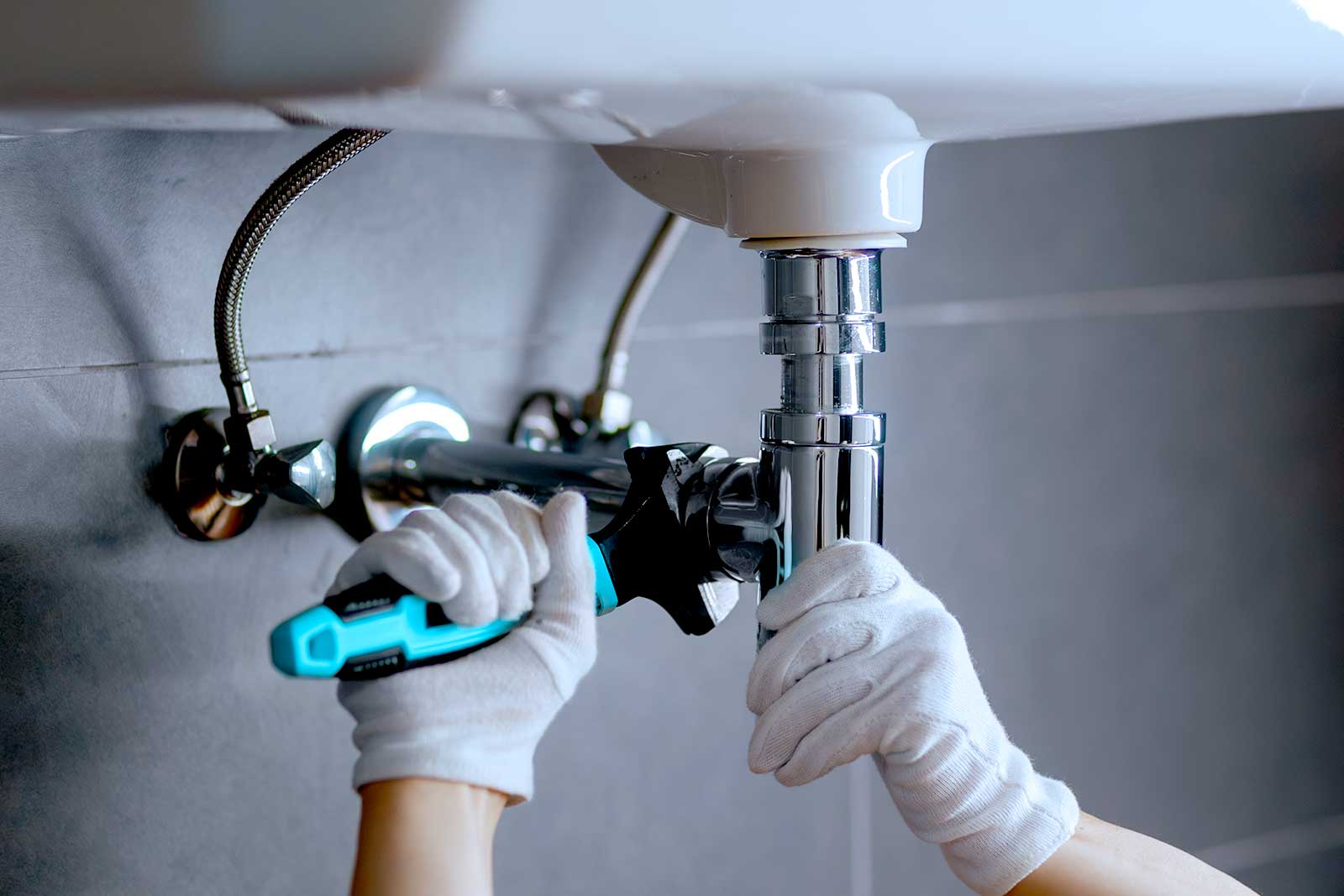 Pessoa ajustando tubulação sob pia