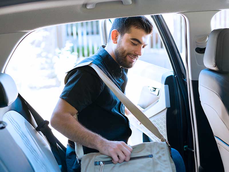 Homem entrando no carro com mochila