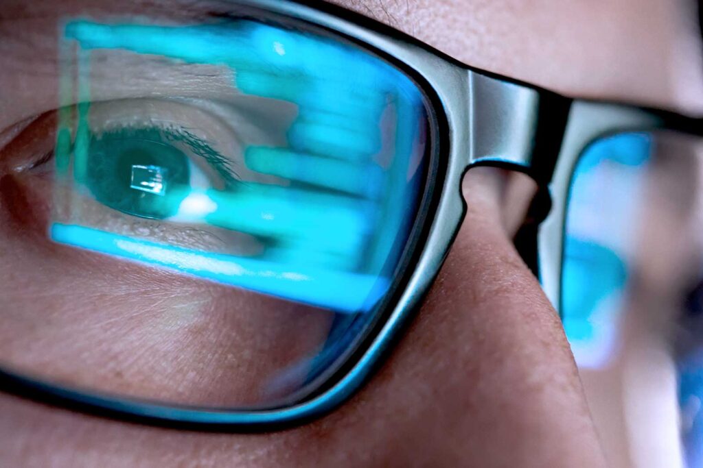 Olhos com óculos refletindo código em tela