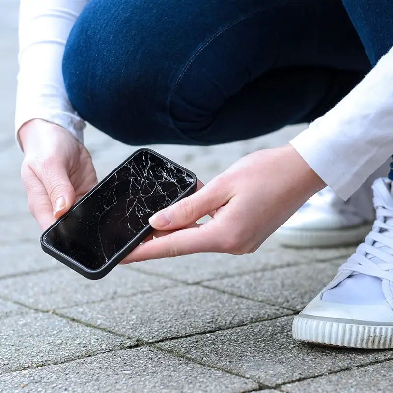 mulher segurando celular quebrado