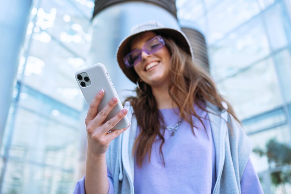 mulher segurando seu celular branco, com um capacete de obras