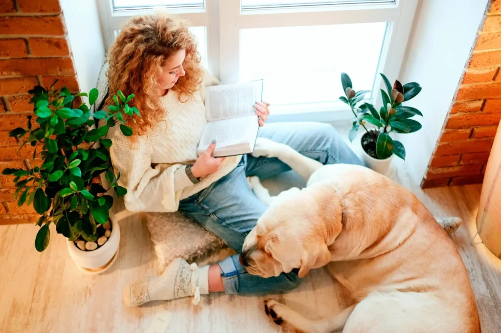 mulher lendo um livro ao lado do seu cahorro