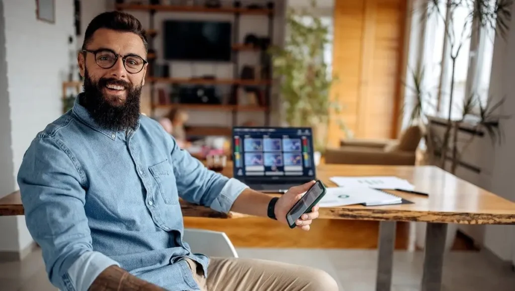 homem sentado segurando seu celular