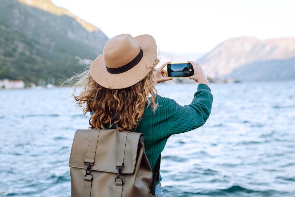 Mulher fotografando um lago nas montanhas