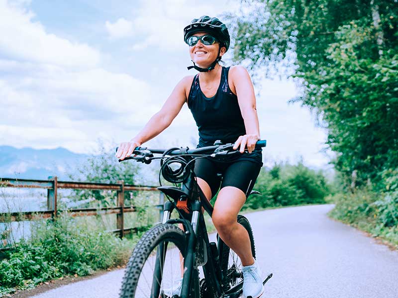 Mulher sorrindo andando de bicicleta ao ar livre.