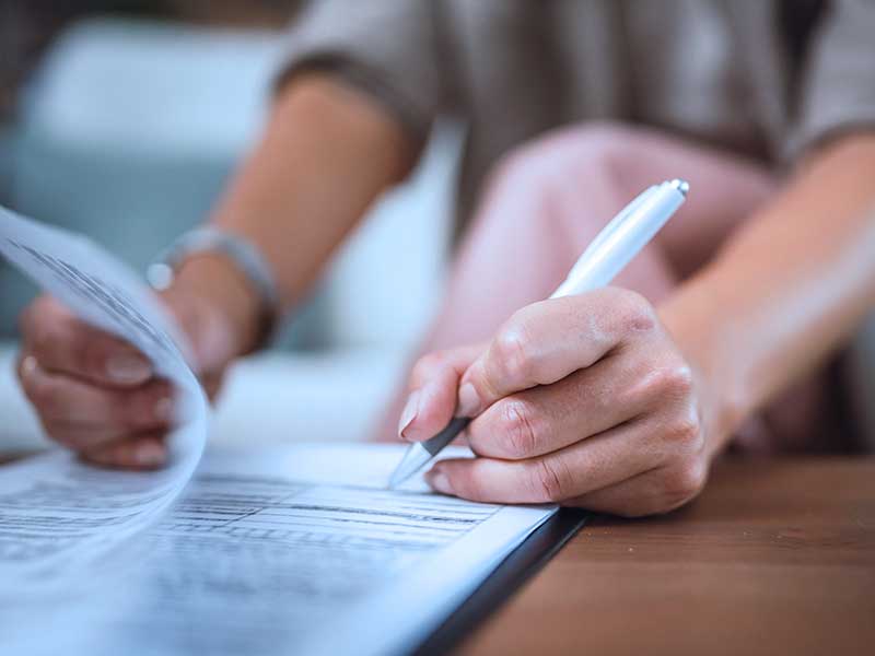 Uma pesssoa preenchendo documentos com uma caneta