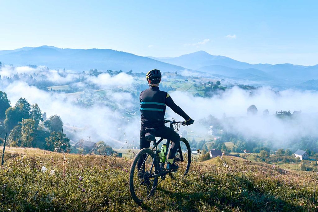 Ciclista admirando vista de montanhas com neblina