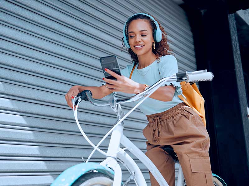 Jovem com fones e celular em bicicleta