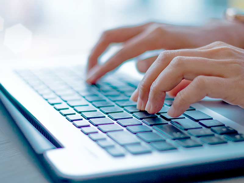 Mãos digitando em um teclado de laptop moderno