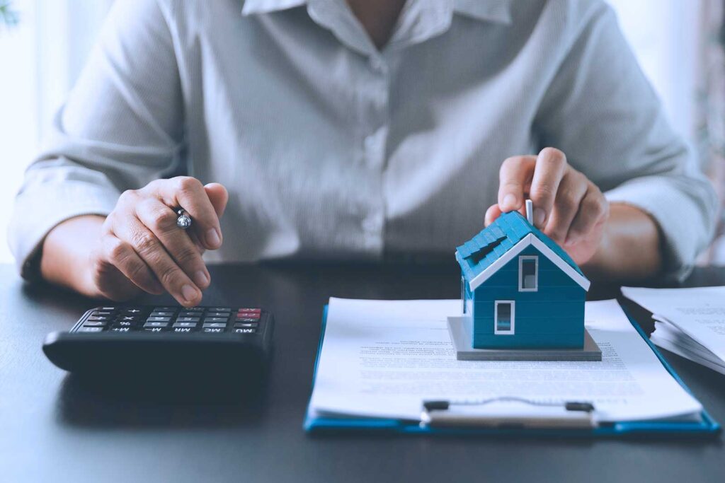 Pessoa analisando financiamento de casa com calculadora.