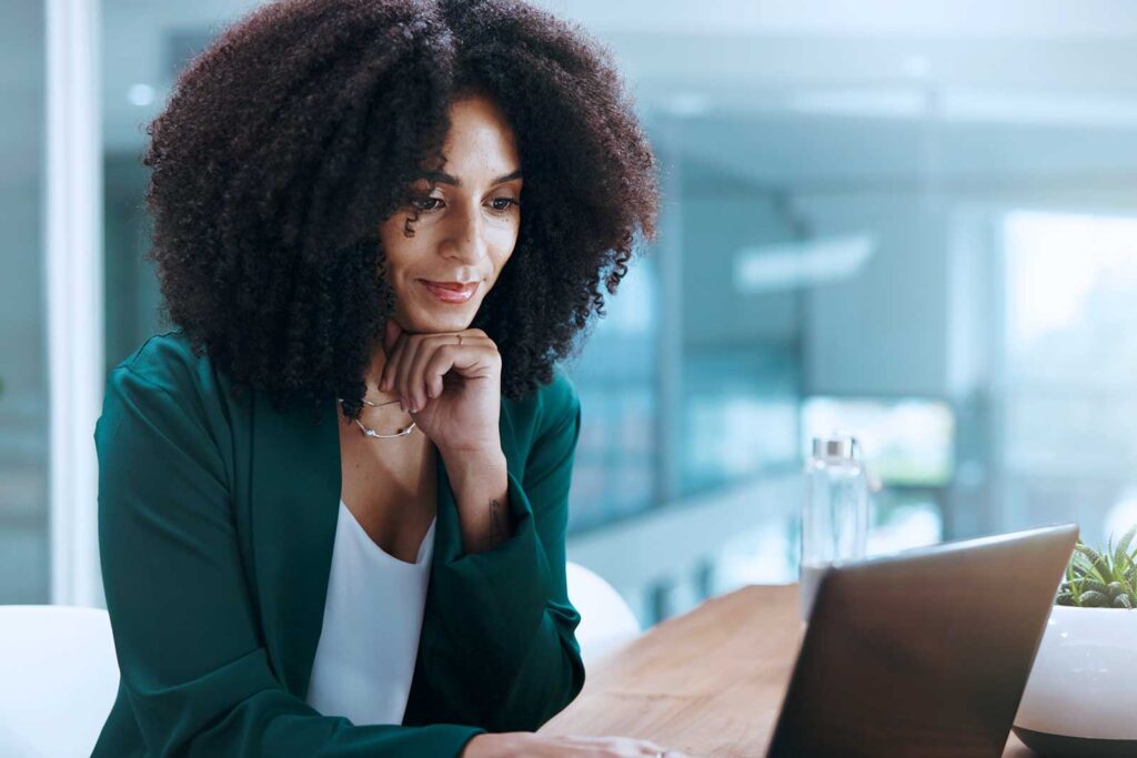 Mulher com cabelo cacheado trabalhando em laptop