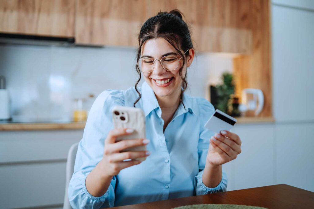 Mulher sorridente fazendo compras online na cozinha