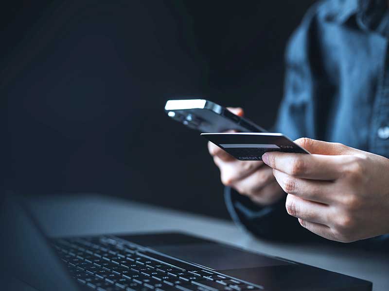 Pessoa usando celular e cartão de crédito para compras online
