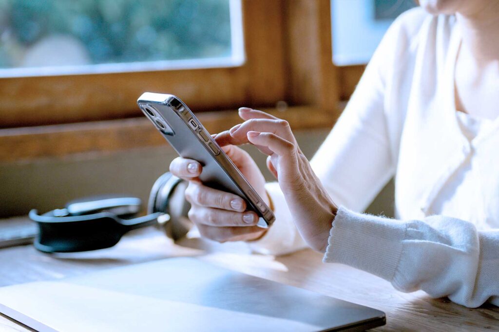 Pessoa usando celular em uma mesa de madeira