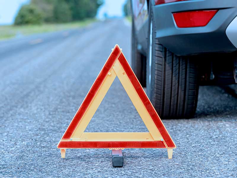 Triângulo de sinalização em estrada com carro ao fundo