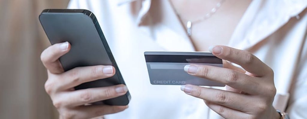 mulher segurando celular com uma mão e na outra um cartão