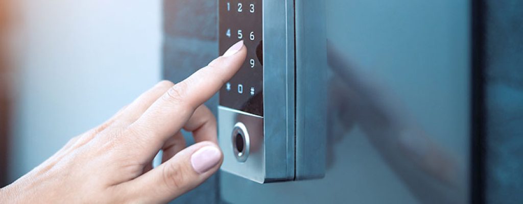 Uma mão usando um teclado numérico de entrada sem chave com leitor de impressão digital integrado.