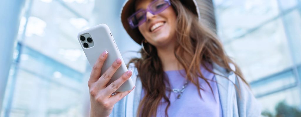 mulher segurando seu celular branco, com um capacete de obras