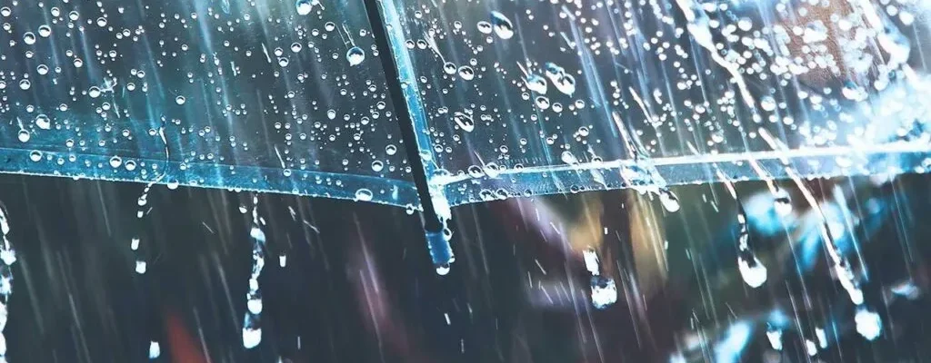 Gotículas de chuva em um guarda-chuva transparente sob uma chuva forte. Água escorre pela superfície do guarda-chuva.