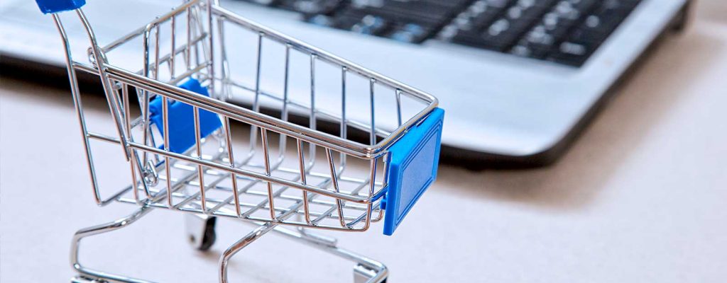 Carrinho de compras ao lado de um laptop