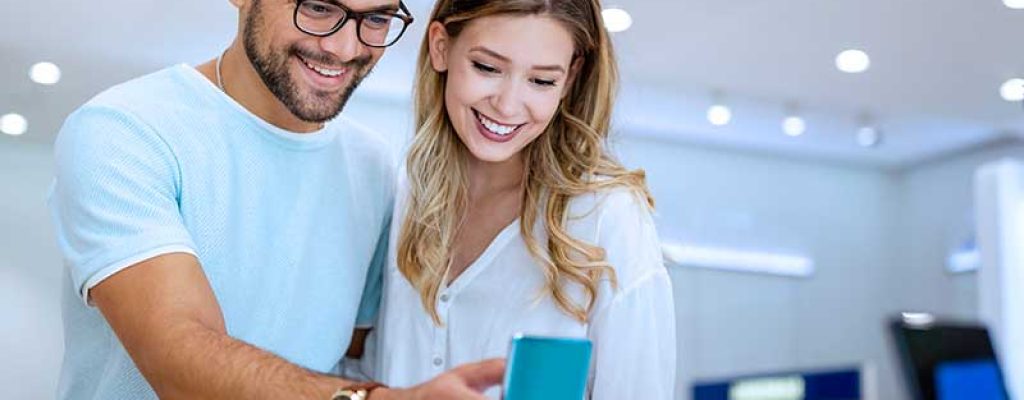 Casal sorridente escolhendo celular em loja