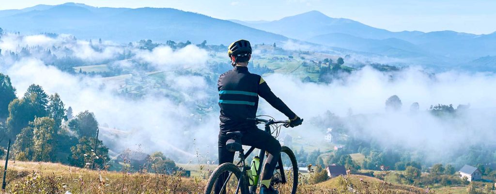 Ciclista admirando vista de montanhas com neblina