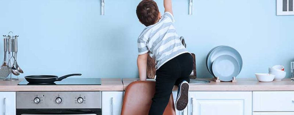 Criança subindo na cadeira na cozinha azul