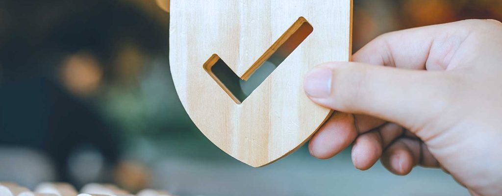 Pessoa segurando um escudo de madeira com marca de verificação