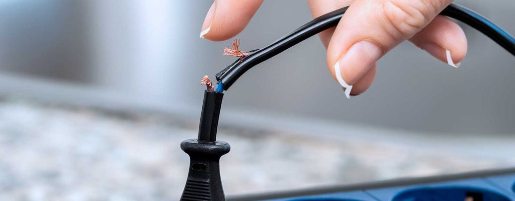 Mão conectando cabo danificado em extensão elétrica