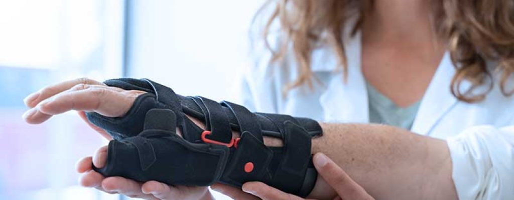 Médica ajustando órtese de braço.
