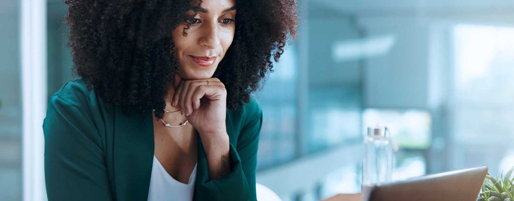Mulher com cabelo cacheado trabalhando em laptop
