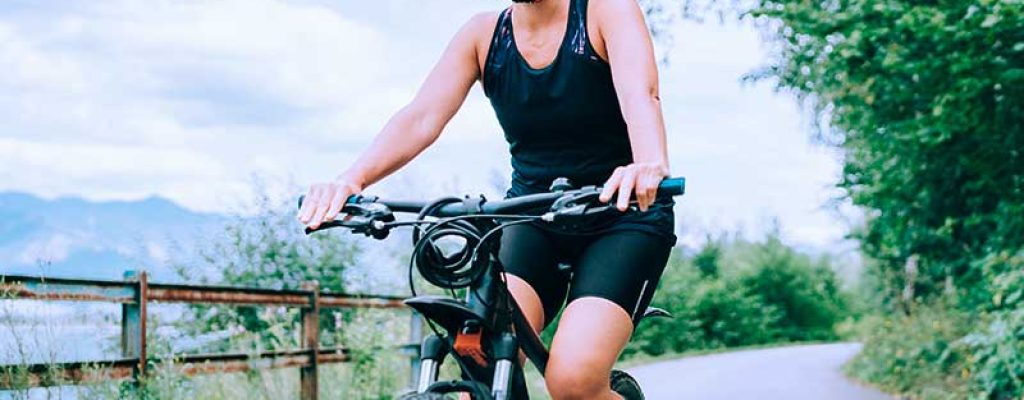 Mulher sorrindo andando de bicicleta ao ar livre.