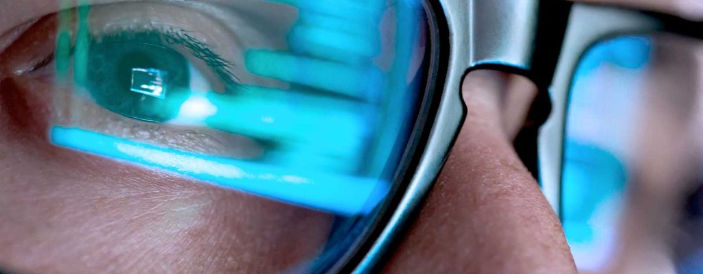 Olhos com óculos refletindo código em tela