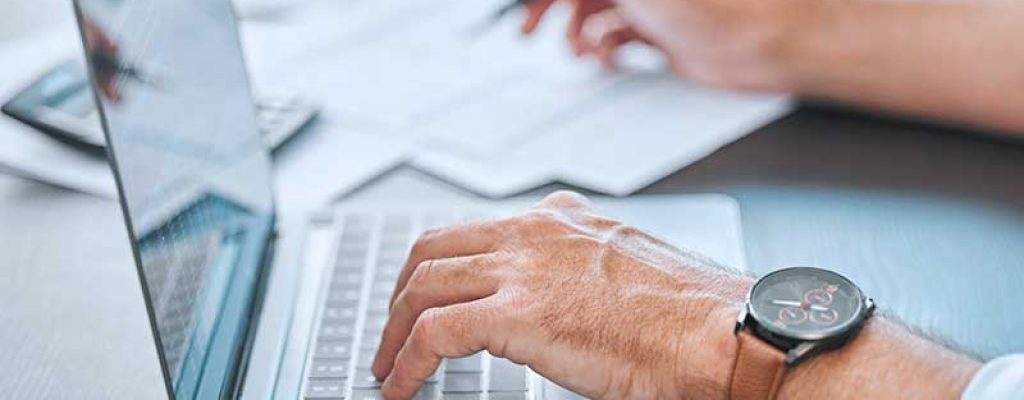 Pessoa digitando em laptop com smartwatch ao redor do pulso
