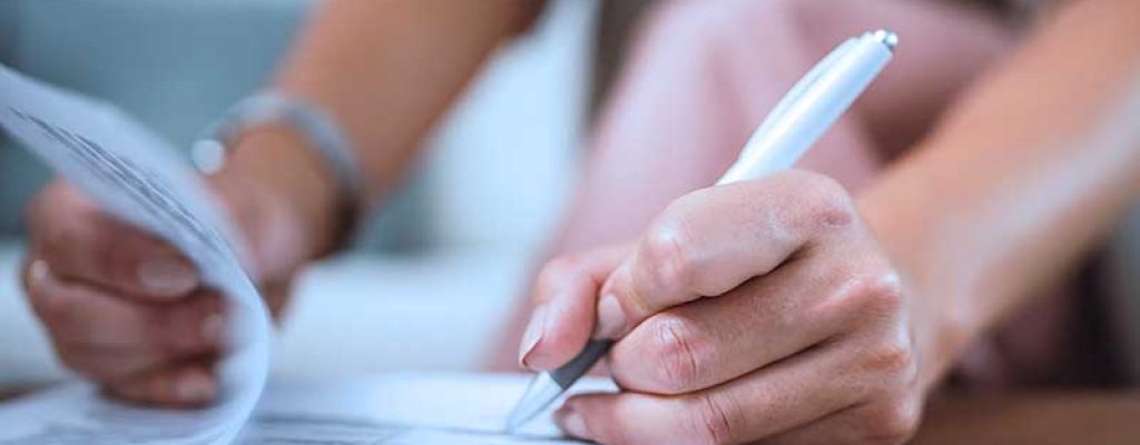 Uma pesssoa preenchendo documentos com uma caneta