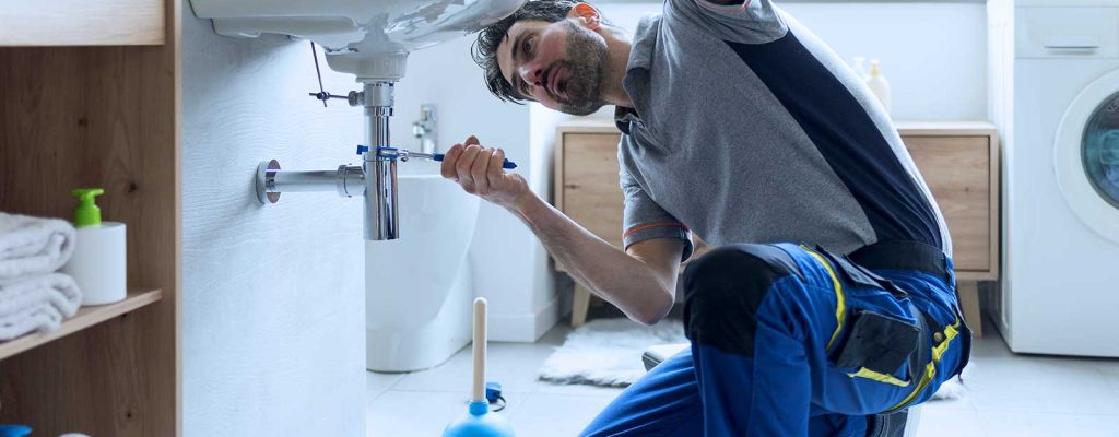 Profissional consertando pia em banheiro moderno