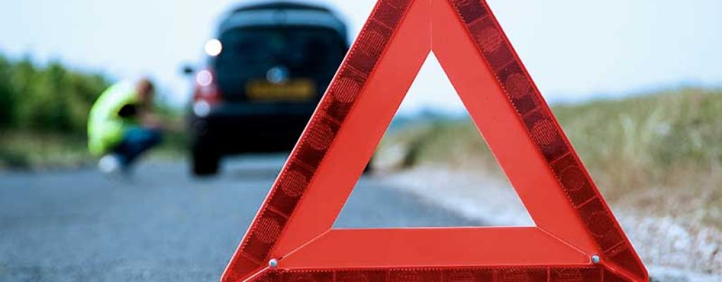 Triângulo de sinalização de emergência de carro, com o carro ao fundo.