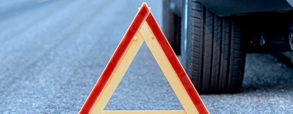 Triângulo de sinalização em estrada com carro ao fundo